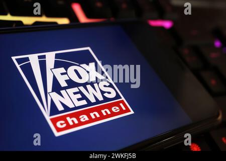 Viersen, Germania - 9 gennaio. 2024: Primo piano del telefono cellulare con il canale Fox news sulla tastiera del computer Foto Stock