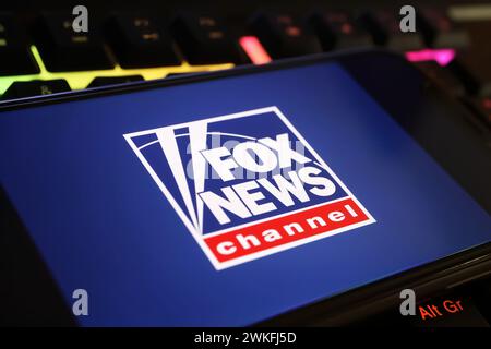Viersen, Germania - 9 gennaio. 2024: Primo piano del telefono cellulare con il canale Fox news sulla tastiera del computer Foto Stock