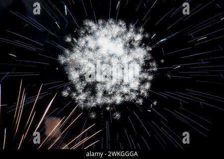 Fuochi d'artificio bianchi e blu con effetto zoom nel cielo notturno. Foto Stock