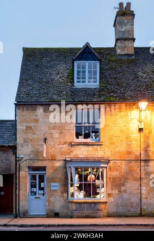 Fai shopping lungo la strada principale al crepuscolo. Chipping Campden, Cotswolds, Gloucestershire, Inghilterra Foto Stock