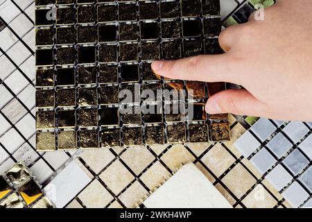 la mano del progettista che sceglie campioni di materiali in pietra per interni è costituita da piastrelle di cemento, pietre di quarzo, pietre artificiali, piastrelle grafiche. vista dall'alto dell'inter Foto Stock