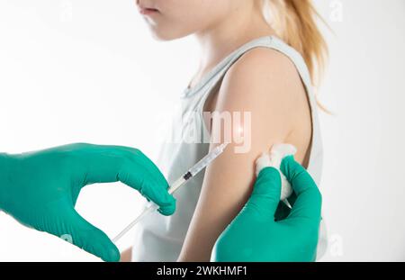 Le mani del medico in guanti medici verdi vaccinano una bambina in spalla contro l'influenza, copia spazio per il testo. Foto Stock