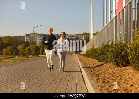 Jogging per coppie senior nel parco per allenarsi insieme nella natura. Concetto di stile di vita sano. Foto Stock