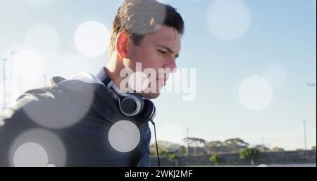 Immagine di punti luminosi sopra un uomo cuacasiano disabile seduto in sedia a rotelle utilizzando lo smartphone Foto Stock