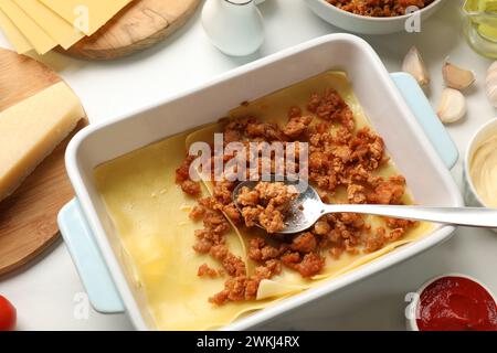 Cottura delle lasagne. Fogli di pasta e carne macinata nel vassoio da forno sul tavolo bianco, vista dall'alto Foto Stock