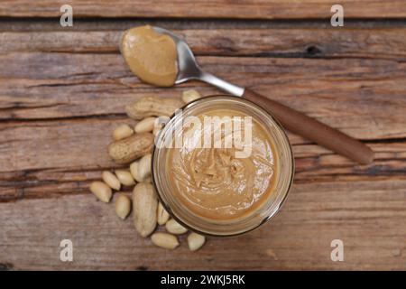 Gustosa pasta di arachidi in vaso e cucchiaio su un tavolo di legno, stendere in piano Foto Stock