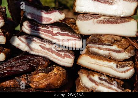 Pancetta esposta e carne secca prodotti domestici presentati per la vendita in un mercato agricolo nel villaggio di Kacarevo, bacon gastro e festival della carne secca Foto Stock