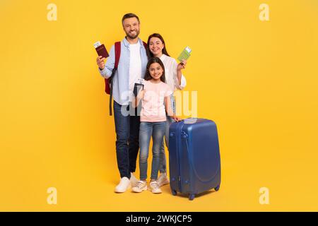 Famiglia gioiosa pronta per il volo mostrando passaporti e biglietti, studio Foto Stock