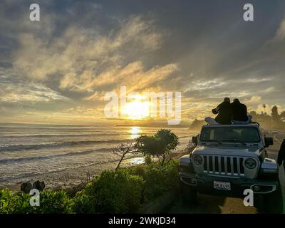 Montecito, California, Stati Uniti. 20 febbraio 2024. Una coppia si siede su una Jeep e guarda il sole tramontare nella bellissima Butterfly Beach, Montecito, durante una pausa nella tempesta di pioggia. Butterfly Lane è stata chiusa il giorno precedente a causa di inondazioni. (Immagine di credito: © Amy Katz/ZUMA Press Wire) SOLO PER USO EDITORIALE! Non per USO commerciale! Foto Stock