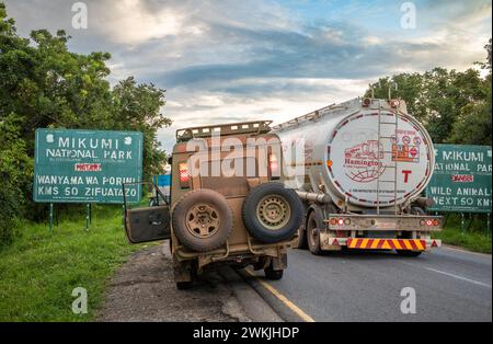 Un camion e un veicolo 4x4 sull'autostrada A7 vicino al cartello di ingresso al Parco Nazionale di Mikumi in Tanzania Foto Stock