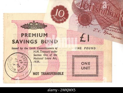 Primo piano di una Premium Savings Bond vintage da £1 e una banconota da dieci scellini del Regno Unito su sfondo bianco. Foto Stock