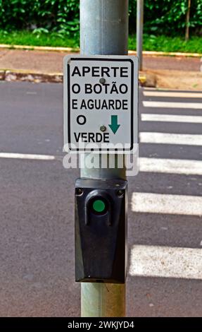 Cartello segnaletico in portoghese con l'indicazione "premere il pulsante e attendere il verde" Foto Stock