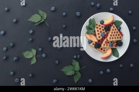 A colazione potrai gustare waffle belgi con mirtilli e miele. Deliziosa pasticceria fatta in casa. Waffle con lamponi, mirtilli, panna acida e legna Foto Stock