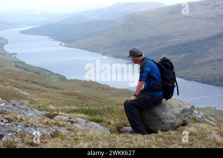 Lone Man (escursionista) Sat on a Rock Loch Arkaig dalla montagna scozzese Corbett Sgurr Mhurlagain, Glen Dessarry, Scottish Highlands, Regno Unito Foto Stock