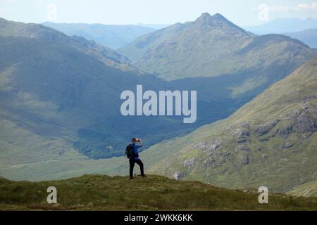 Uomo (escursionista) che scatta foto di Glen Dessarry e del Corbett 'Bidean A' Chabair' dalle Highlands scozzesi di Corbett 'Fraoch Bheinn', Scozia, Regno Unito. Foto Stock