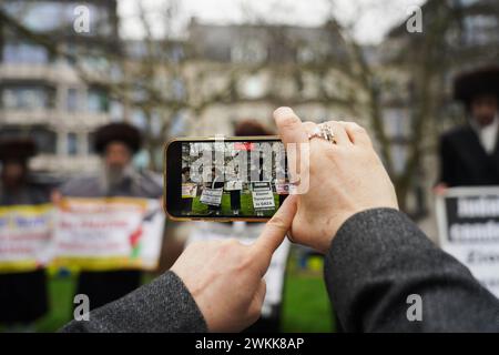 Una donna filma i membri del gruppo ebraico haredi anti-sionista Neturei Karta mostrando il loro sostegno alla Palestina come centinaia di migliaia di persone ottengono Foto Stock