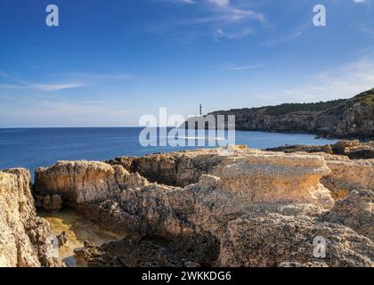 Una vista della costa frastagliata del nord di Ibiza a Portinatx con il faro di Punta de Moscarter sullo sfondo Foto Stock