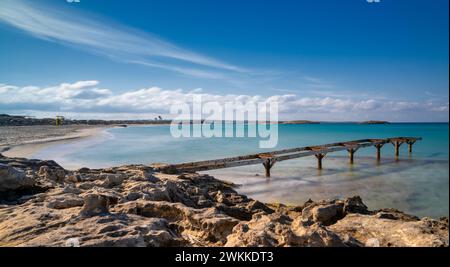 Un vecchio molo conduce alle acque turchesi della spiaggia di Ses Illetes nel nord di Formentera Foto Stock