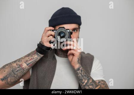 Bellissimo fotografo hipster professionista che tiene in mano una fotocamera mirrorless e scatta foto in studio Foto Stock