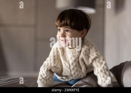 Adorabile ragazzo dopo aver dormito nel suo letto con il giocattolo. Bambino piccolo felice che gioca con il coniglietto giocattolo. Concetto di famiglia, vacanza, infanzia Foto Stock