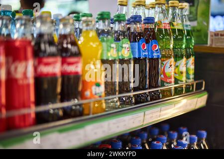 Scaffale in negozio, bibite di marche diverse. Coca Cola, Fanta, 7 in su, Pepsi. Lattine in alluminio, bottiglie in vetro di varie dimensioni. Editoriale sulle bevande, popolare CA Foto Stock