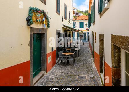 Un piccolo caffè sul marciapiede in uno stretto vicolo acciottolato nel villaggio sul mare di Camara de Lobos, in Portogallo, sull'isola Canaria di Madeira. Foto Stock