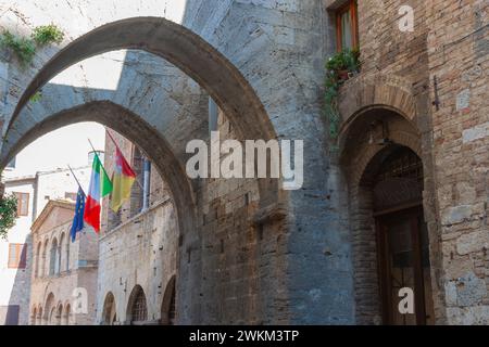 San Gimignano, Italia - 4 aprile 2011; tipiche strade medievali della città europea ed edifici con tre bandiere Foto Stock