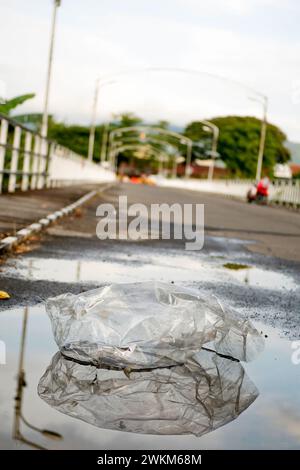 Spazzatura di plastica trasparente in una pozzanghera per strada Foto Stock