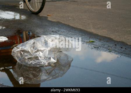 Spazzatura di plastica trasparente in una pozzanghera per strada Foto Stock