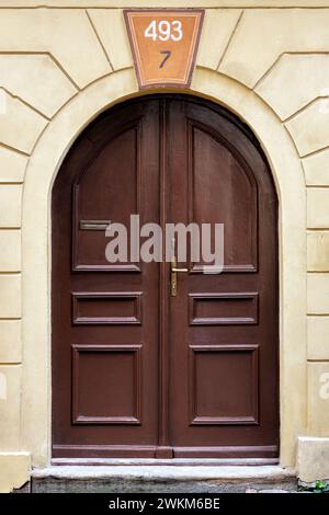 Porta di legno marrone con arco contro una parete gialla. Dalla serie Doors of the World. Foto Stock