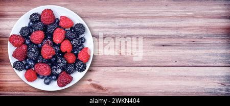 Bacche in una ciotola. A colazione e per dessert ci sono molti frutti di bosco. lampone, mora, mirtillo, fragola. Banner. Vista dall'alto. La piatta Foto Stock