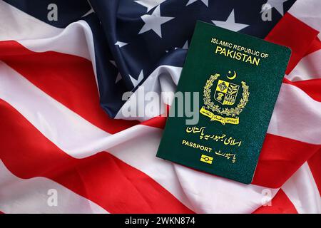 Passaporto verde della Repubblica Islamica del Pakistan sullo sfondo della bandiera nazionale degli Stati Uniti da vicino. Concetto di turismo e diplomazia Foto Stock