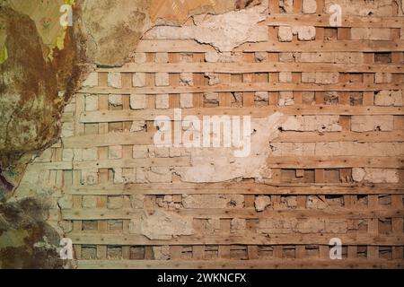 Intonaco parzialmente demolito e parete in reticolo di legno in camera all'interno di una vecchia casa degli anni '1800. Foto Stock