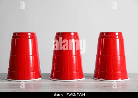 Gioco di shell. Tre tazze rosse su un tavolo di legno Foto Stock