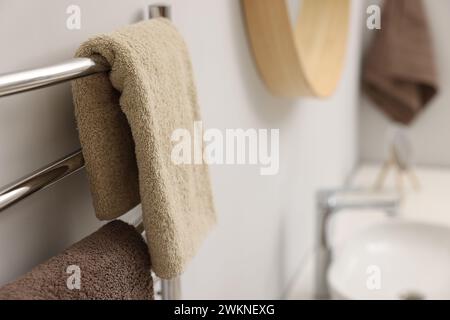 Portasciugamani riscaldato con asciugamani marroni in bagno, primo piano Foto Stock