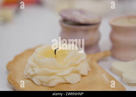 donna che produce candele a casa, primo piano di mani femminili che versano cera liquida gialla dalla padella alla muffa di silicone. Le candele in vetil tagliate di alta qualità rendono le candele aromatiche Foto Stock