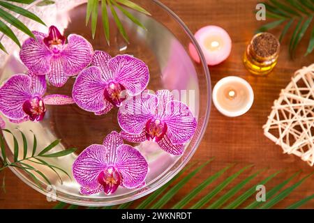 Accordo di bellezza con olio aromatico, candela bruciata e orchidea Foto Stock