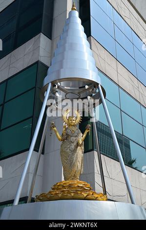 Raffigurazione della dea indù Lakshmi come un'elegante donna di colore dorato in piedi su un loto in un santuario piramidale, Bangkok Foto Stock