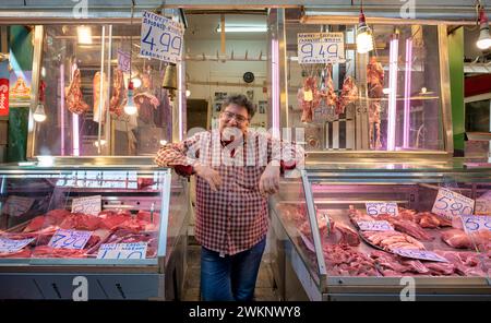 Macellaio, commerciante di carne che si posa orgogliosamente davanti al suo bancone, esposizione di carni fresche, macelleria, cibo, mercato Kapani, Vlali, Salonicco Foto Stock