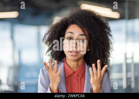 Serio ceo afroamericano nella conferenza di orientamento con i colleghi e sollevamento delle braccia con le dita spalmate. Imprenditrice donna incentrata che spiega ai dipendenti una nuova strategia di sviluppo. Foto Stock
