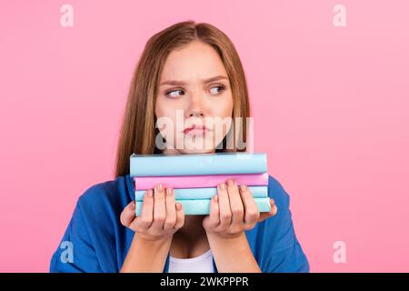 Foto di una camicia azzurra annoiata che regge un libro sullo sfondo di colore rosa isolato in uno spazio vuoto Foto Stock