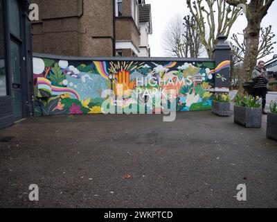 Un vivace murale di Street art dipinto su una parete esterna bianca sulla Avenue di Highams Park, Londra, Regno Unito, E4. Le opere d'arte raffigurano i monumenti locali e le scene dell'area di Highams Park, che fungono da opera d'arte pubblica concentrata sulla comunità nel cuore del quartiere. Situato nel London Borough of Waltham Forest, il murale contribuisce all'estetica suburbana della sfilata dello shopping vicino alla stazione ferroviaria di Highams Park Foto Stock