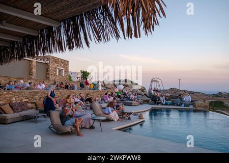 IOS, Grecia - 17 settembre 2023: Veduta di varie persone sedute di fronte ad una piscina presso un lounge bar che si gode il tramonto a iOS Grecia Foto Stock