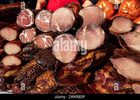 Deliziosi pezzi di carne affumicata esposti per la vendita nel mercato presentato per la vendita in un mercato agricolo nel villaggio di Kacarevo, pancetta gastro e carne secca Foto Stock