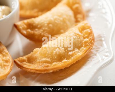 Antipasti caldi con Mini Chebureki e salse isolate su sfondo bianco della tavola. Menu antipasto del ristorante con boccali croccanti bruciati, Pies o Samosa con Spicy Sause da vicino Foto Stock