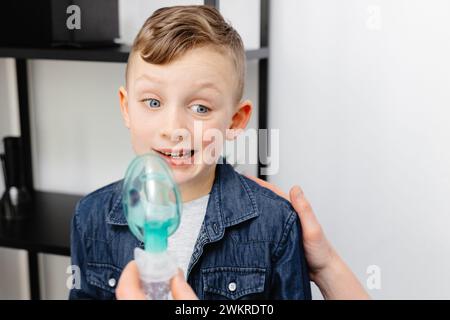 Il ragazzo carino mostra emozione dispiaciute prima di inalare. Foto Stock