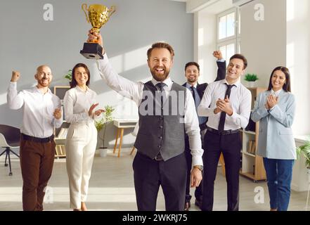 L'uomo d'affari felice e il responsabile del team aziendale riceve una tazza d'oro come premio aziendale Foto Stock