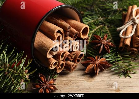 Molti bastoncini di cannella, stelle di anice e rami di abete su un tavolo di legno, primo piano Foto Stock