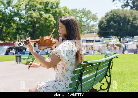 giovane donna latina artista venezuelana violinista busker nel parco di buenos aires, che suona il violino lavorando come artista di strada. Foto Stock