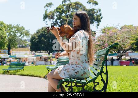 giovane donna latina artista venezuelana violinista busker nel parco di buenos aires, che suona il violino lavorando come artista di strada. Foto Stock